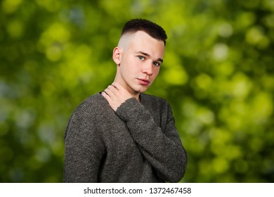 Portrait White Yong Guy In Gray Sweater And Short Haircut, On Green Bokeh Background