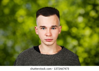 Portrait White Yong Guy In Gray Sweater And Short Haircut, On Green Bokeh Background