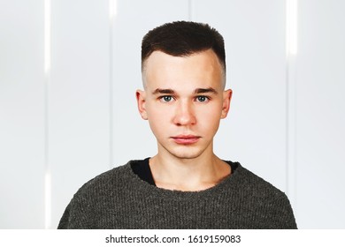 Portrait Of White Yong Guy In Gray Sweater And Short Haircut.