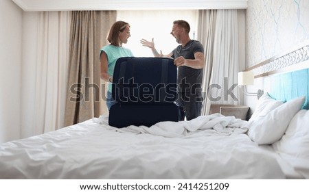 Portrait of wife and husband screaming on each other and argue, pack stuff in suitcase, couple fight, divorce. Farewell, family, goodbye, leaving concept