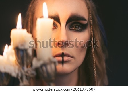 portrait of a witch with candle. Halloween mystical atmosphere. Celtic mythology goddess Valkyrie. Spiritualism spell rite. Masquerade makeup costume. Magic witchcraft occultism. Mystic mood lifestyle