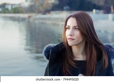 Portrait Of A Woman, 30s, Standing At The Beach In Winter Looking Away, Thinking, Outdoors, Sunset Light.