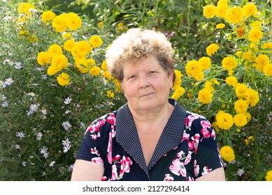 Portrait of a woman 60s years old against the background of yellow flowers in the garden