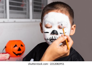 Portrait Of Woman Applying Color Brush To Child Face For Party At Home, Family Asian Mother And Kid Son Getting Makeup Halloween Face Painting Look Like Ghost, Happy Halloween Day Concept