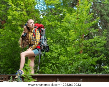 Portrait of a woman with a backpack walks through the forest with binoculars. Ecotourism concept.