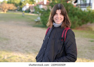 Portrait Of Woman With Bagpack Walking In Pathway In Winter Day