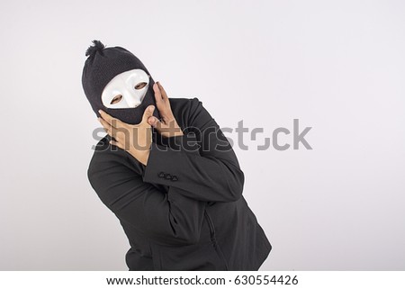 Portrait of woman in balaclava standing with arms crossed.
