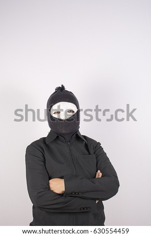 Portrait of woman in balaclava standing with arms crossed.
