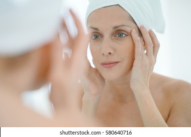 portrait of woman in bathroom applying moisturizing cream
