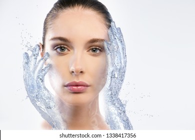 Portrait of woman with beautiful face and perfect skin just cleaned from impurities touching it gently with 3d water hands to show how soft, smooth and pure  it is.
