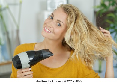 portrait of woman blowdrying her hair