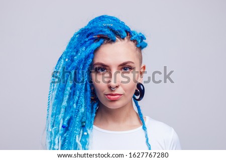 Portrait of a woman with blue dreadlocks and a piercing. Informal young woman.