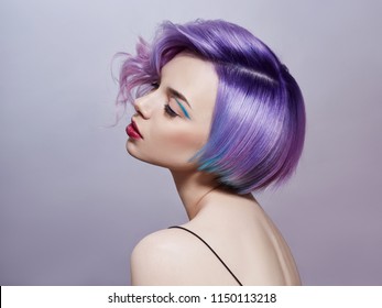 Portrait of a woman with bright colored flying hair, all shades of purple. Hair coloring, beautiful lips and makeup. Hair fluttering in the wind. Sexy girl with short  hair. Professional coloring