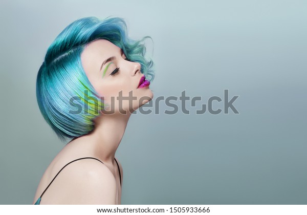 Portrait of a woman with bright colored flying
hair, all shades of blue purple. Hair coloring, beautiful lips and
makeup. Hair fluttering in the wind. Sexy girl with short  hair.
Professional coloring