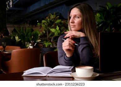 Portrait of a woman in a cafe. The woman thinks. Mental health.
 - Shutterstock ID 2311236223