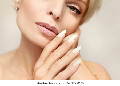 Portrait of a woman with clean healthy skin and a long manicure with milk nail Polish close-up.