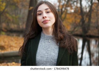 portrait of a woman with dark long hair in a green coat in an autumn park