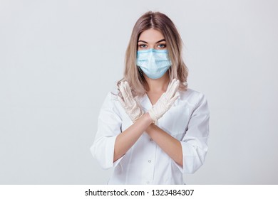 Portrait of woman doctor with face mask and white medical gloves shows stop sign - Shutterstock ID 1323484307