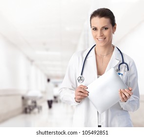 Portrait of woman doctor at hospital corridor, holding tablet computer, looking at camera, smiling. - Powered by Shutterstock