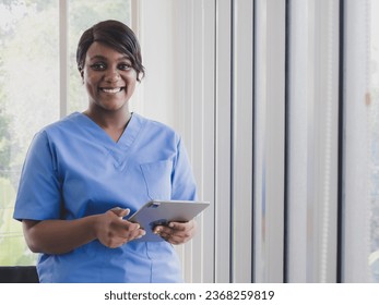 Portrait woman doctor nurse carer physical therapist black African-American one people smile stand looking hand holding tablet information for patients inside window in hospital indoor room service. - Powered by Shutterstock