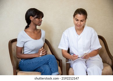 Portrait Of Woman And Doctor Or Nurse Writing Down Prescription. Serious Young African American Female Patient Wearing T-shirt And Jeans Having Consultation In Doctors Office. Visiting Doctor