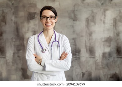 Portrait Of A Woman Doctor With Stetoscope Looking At Camera. Smiling Female Doctor In A Clinic Background.