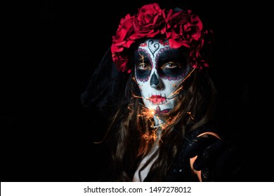 Portrait of woman dressed as catrina, skull to honor the dead in Mexico. Dressed with white face, black eyes and a bouquet and wreath of red roses. black background and light rembrandt. - Powered by Shutterstock