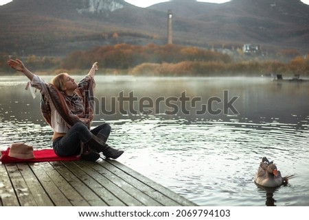 Portrait of woman dressed in poncho and look to the lake, enjoy life, happy in moment