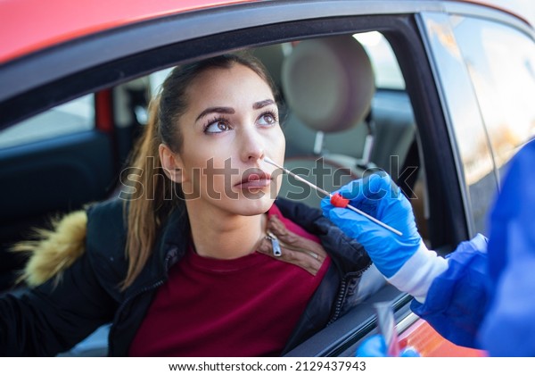 Portrait of woman drive thru coronavirus\
covid-19 test by medical staff with PPE suit by nose swab. New\
normal healthcare drive thru service and medical\
concept.