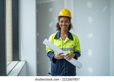 Portrait Of Woman Engineer With Full Version Enineering Cloth, Holding Roll Of Plan Paper Looking To Camera With Smile Of Happiness, Teeth Smile.