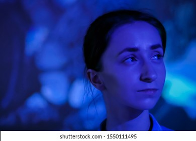 Portrait Of Woman Face Looking Around At Modern Immersive Exhibition With Low Light Illumination And Colorful Video Art Installation. Education, Digital Art And Entertainment Concept