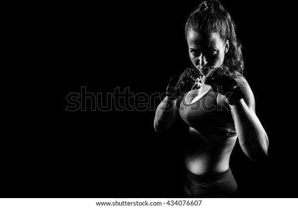 Portrait of woman with fighting stance against
black background