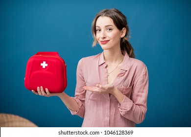 Portrait of a woman with first aid kit on the blue wall background