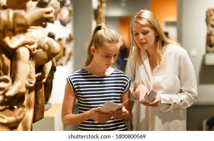 Portrait of woman with girl holding guidebook, standing in museum of ancient sculpture - Shutterstock ID 1800800569