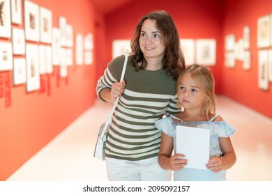 Portrait Of Woman With Girl Looking At Modern Painting In Museum Of Art