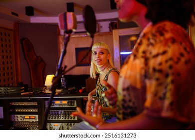 Portrait of woman guitar player recording new music with multiracial music band in a studio with their producer and sound engineer. Focus on a blond female playing guitar. Copy space. - Powered by Shutterstock