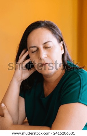 Portrait woman in her 50's with loose brown hair and eyes closed, her hand resting on her face, pensive and relaxed. Concept of mental health and mature age
