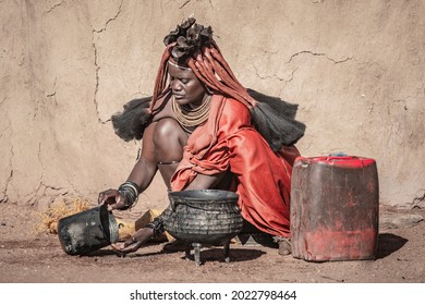 Portrait Of A Woman From The Himba Tribe Preparing Food In A Traditonal Himba Village In Namibia, Africa. Himbas Are An African Tribe Located In North Namibia And South Angola.