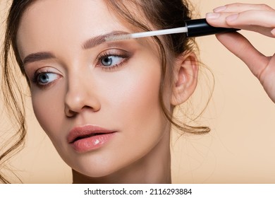Portrait Of Woman Holding Brush Of Eyebrow Gel Isolated On Beige