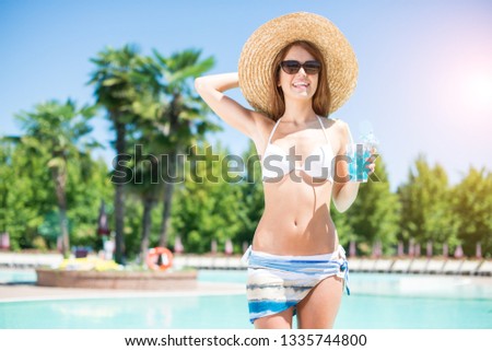 Portrait of a woman holding a cocktail on the poolside