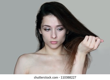 Portrait Of Woman Holding Damaged Dry Hair And Sad Looking Isolated On Grey Background