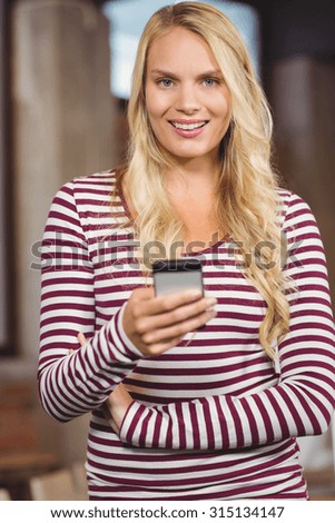 Portrait of woman holding smart phone in creative office
