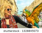 Portrait of woman interacts with a parrot with open wings at Bird Souq inside Souq Waqif, the old market tourist attraction in Doha center, Qatar. Caucasian traveler in Middle East, Arabian Peninsula.