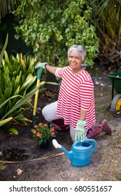 Portrait Of Woman Kneeling On Field While Gardening In Yard