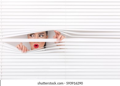 Portrait of a woman looking through out the blinds - Powered by Shutterstock