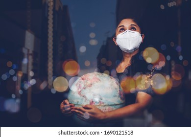 Portrait Of Woman With Mask N 95  Is Look At The Sky And Holding World Globe While Praying To God Over Black Background With Bokeh Light In The Night. Virus Covid 19 Crisis, Disease  Concept 