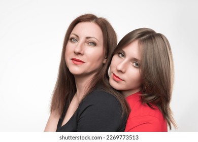 Portrait of woman mother and teenager daughter looking at camera. Mom generation x in black t-shirt and teenager gen z in red t-shirt. Studio shot family on white background. Part of photo series