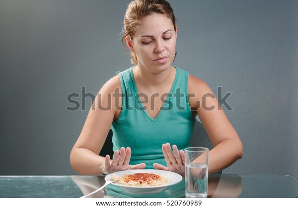 Portrait of woman with no appetite in front of\
the meal. Concept of loss of\
appetite