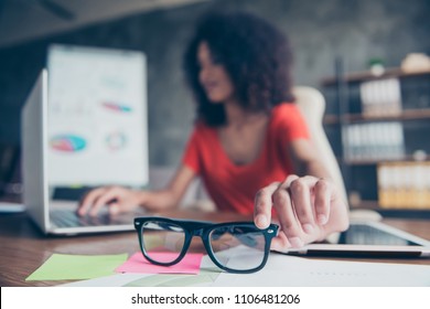 Portrait Of Woman On Blurred Background Sitting At Desktop Browsing On Laptop Holding  Focused Protective Optical Eye Glasses For Computer Bad Vision. Test Examination Health Care Concept