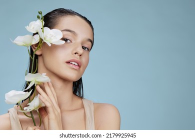 portrait woman orchid near face cosmetics clean skin tenderness blue background